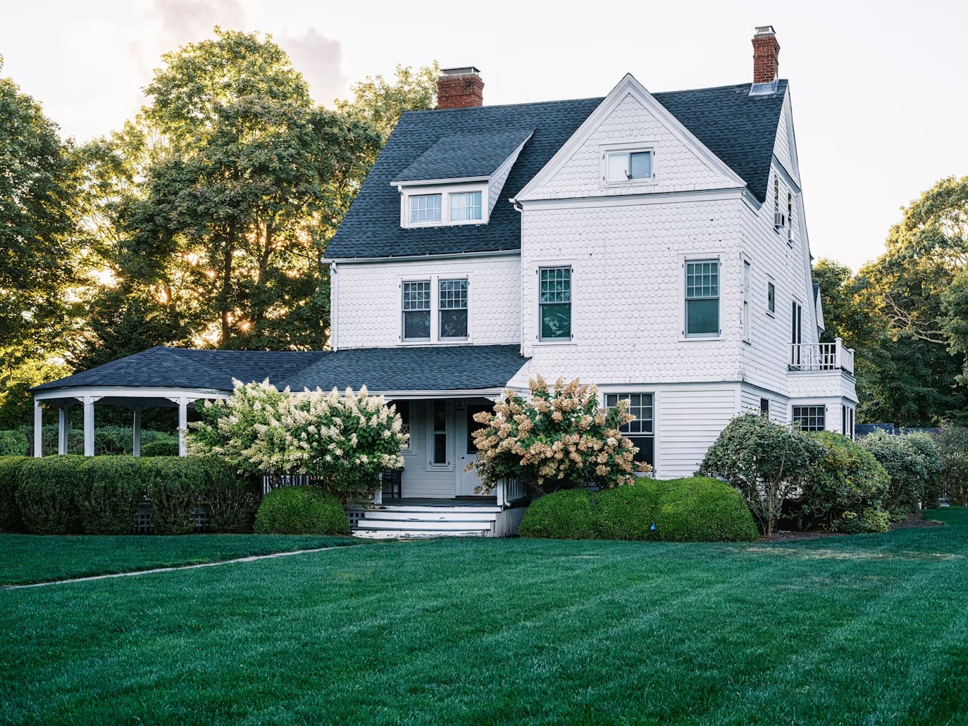 Illustrative white coastal home surrounded by a green garden